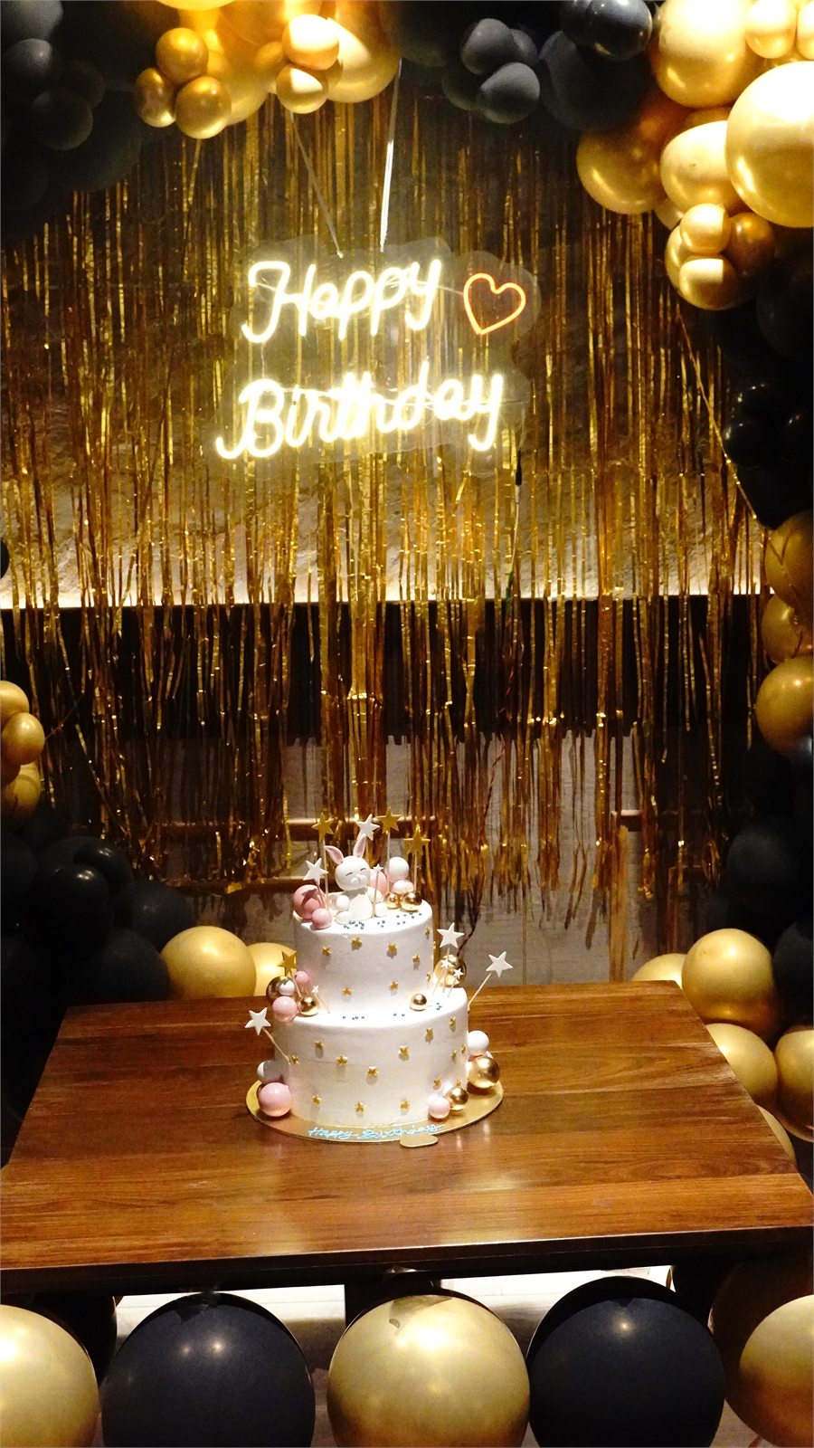 Black and gold birthday backdrop with cake at Nineteenth May